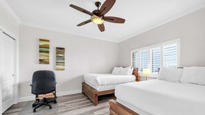 Un dormitorio con ventilador de techo, dos camas, un escritorio y una ventana con persianas.