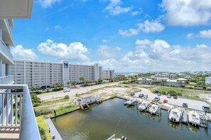 A marina with boats docked, a parking lot, and a hotel building with multiple floors and balconies. - Habor Landing 402B harbor views nearby beach access (Destin)