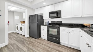 Una cocina moderna con armarios blancos, un refrigerador negro, un microondas, una estufa y un lavavajillas.