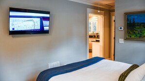 Quarto de hotel com uma cama, televisão na parede e um quadro.
