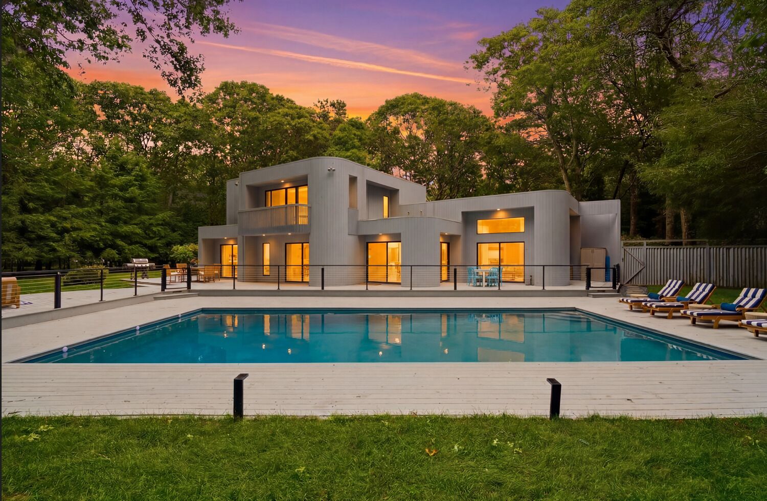 Ett modernt hus i två våningar med en swimmingpool och en uteplats.