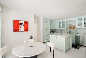 Una cocina moderna con armarios azul claro, una isla blanca y una mesa de comedor redonda con sillas.