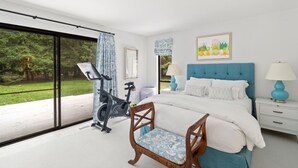 Ein Schlafzimmer mit einem Bett, einem Sessel, einem Nachttisch, einer Lampe, einem Fenster und einem Heimtrainer.