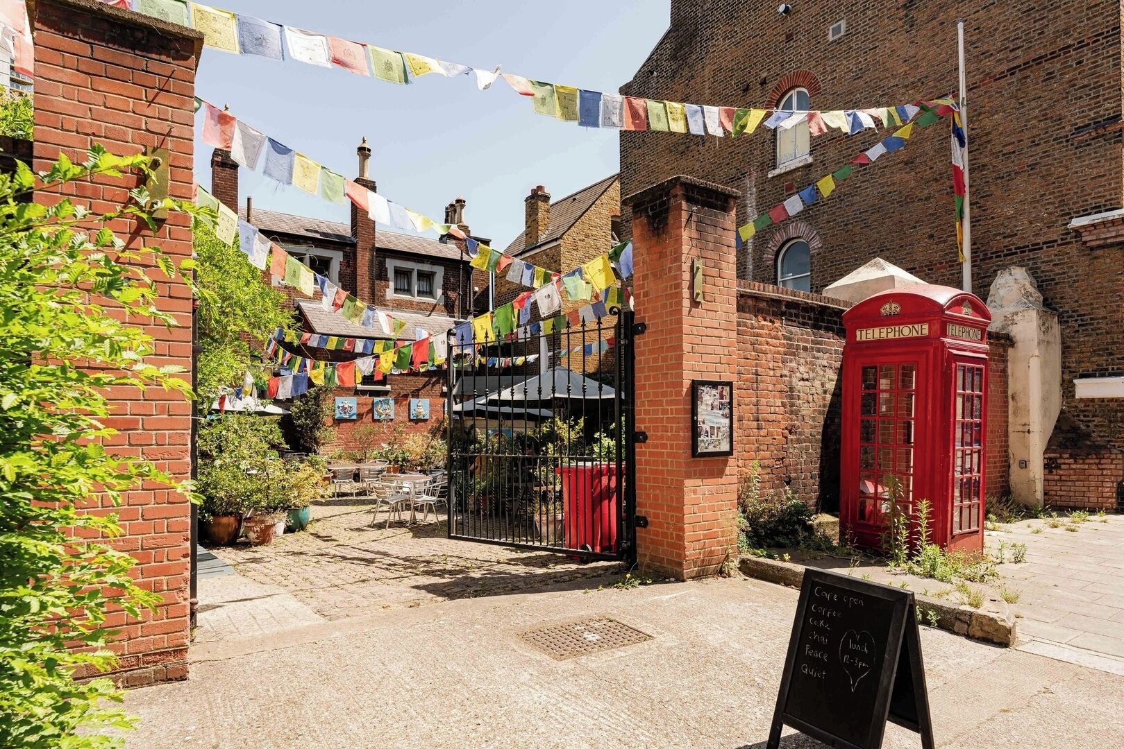 A traditional British pub with a red telephone booth, a brick building, and a signboard for coffee and cake.