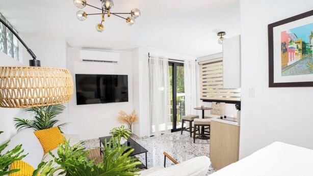 Una sala de estar moderna con televisor, sofá y comedor.