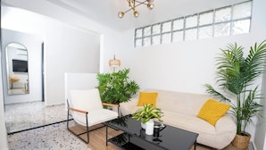 Una sala de estar moderna con sofá, sillón, mesa de centro y plantas en macetas.