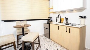 Una cocina compacta con una mesa redonda, dos sillas, una encimera con un lavamanos y una estufa.