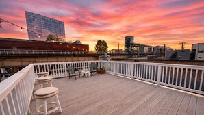 A wooden deck with white railings, seating, and a sunset view. - Cozy 2BR Near McCormick & Wintrust with Optional Parking (Chicago)