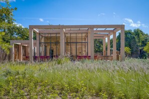 A modern structure with a glass facade, surrounded by natural vegetation. - Elegant 2BR Condo at The Village Corasol (Playa del Carmen)