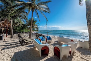 A beach with lounge chairs and a palm tree. - Elegant 2BR Condo at The Village Corasol (Playa del Carmen)