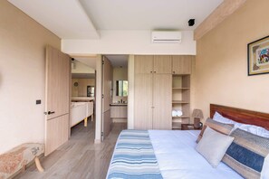 Ein Schlafzimmer mit einem Bett, einem Holzschrank, einer Bank und einer Küchenzeile.