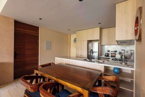 Eine kleine Küche mit Holztisch und -stühlen, einem eingebauten Backofen und einem Spülbecken.