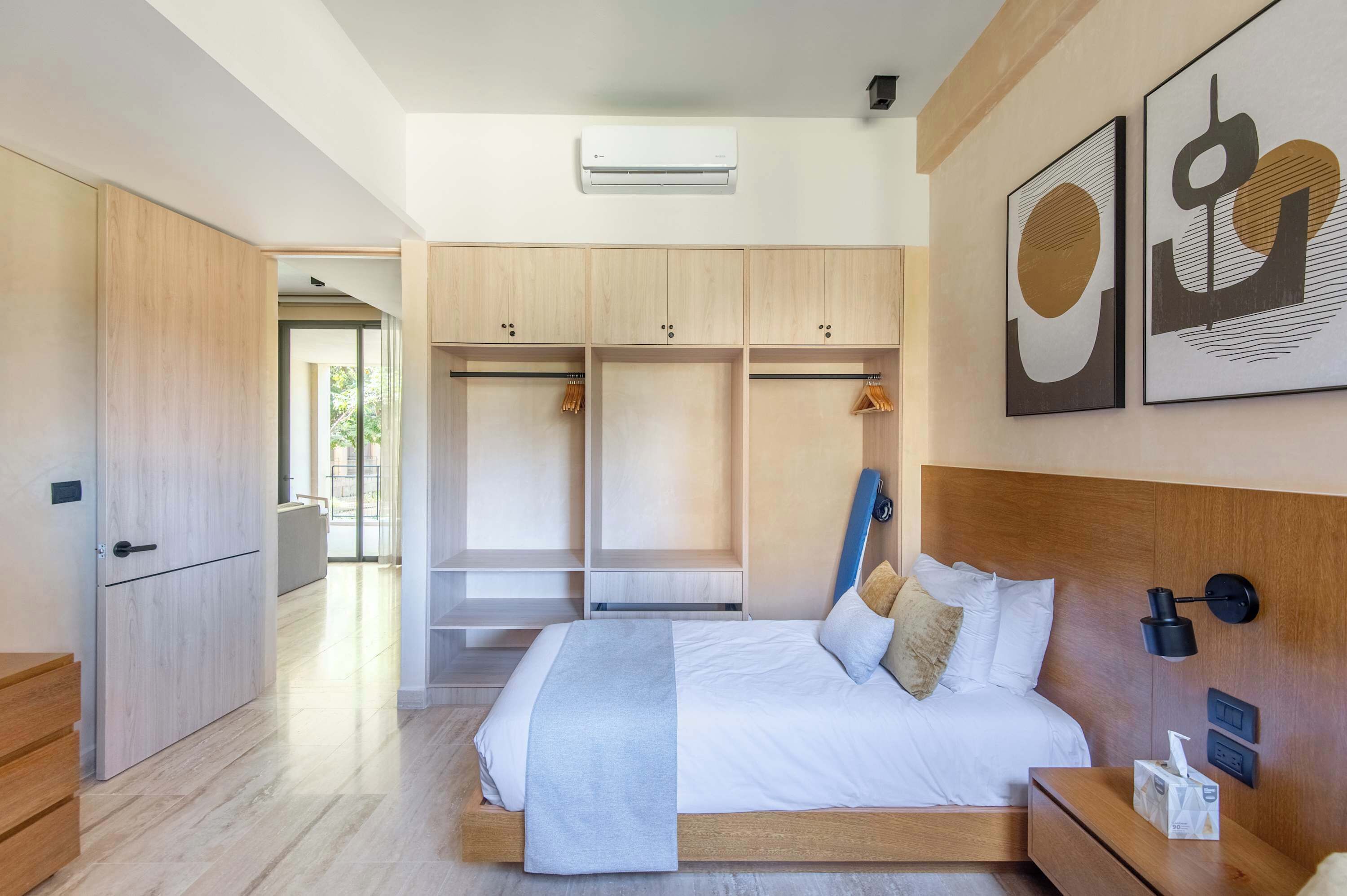Quarto moderno com cama grande, armário embutido e vista para o exterior.