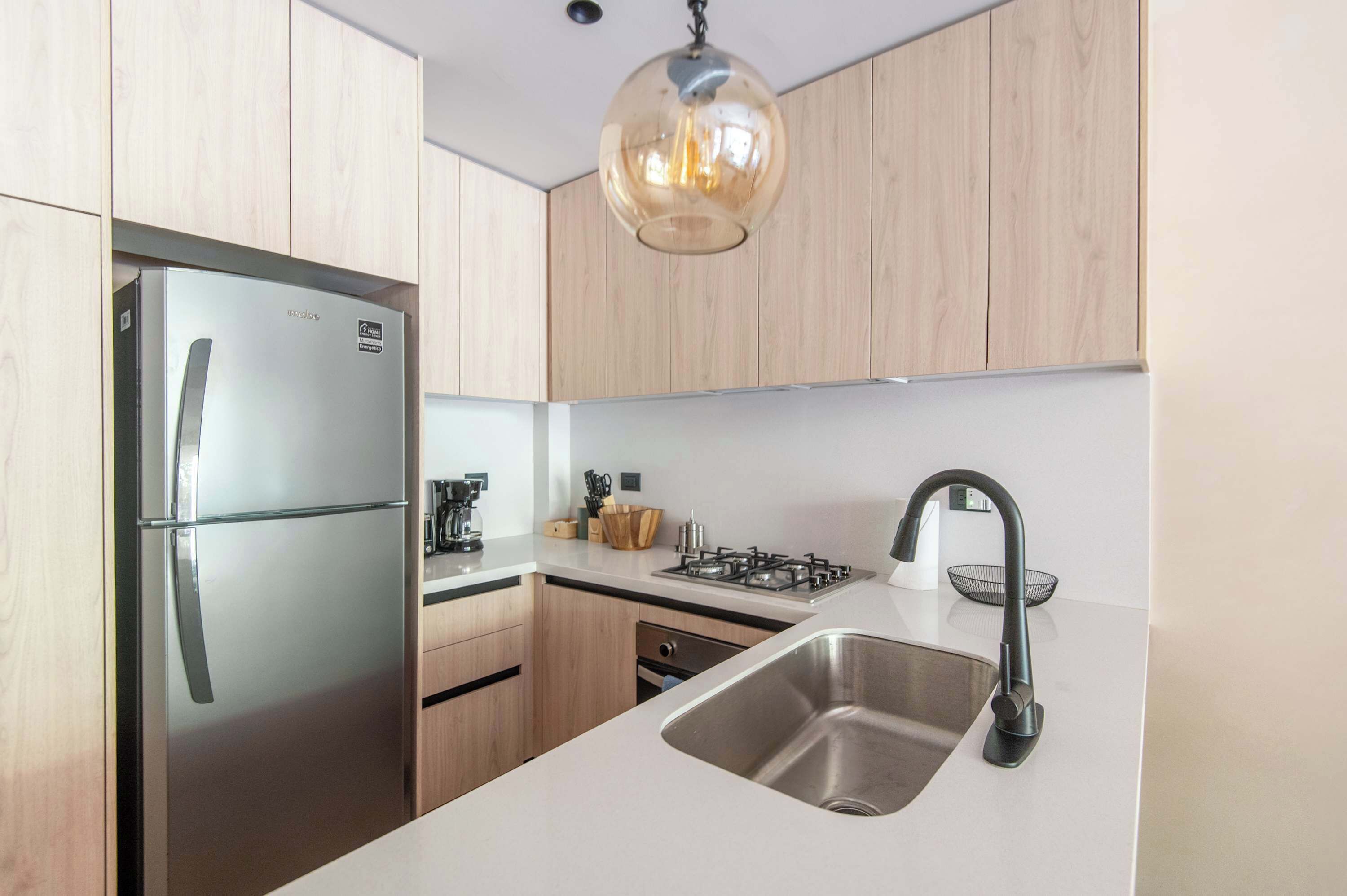 A modern kitchen with a stainless steel refrigerator, a gas stove, and a sink.