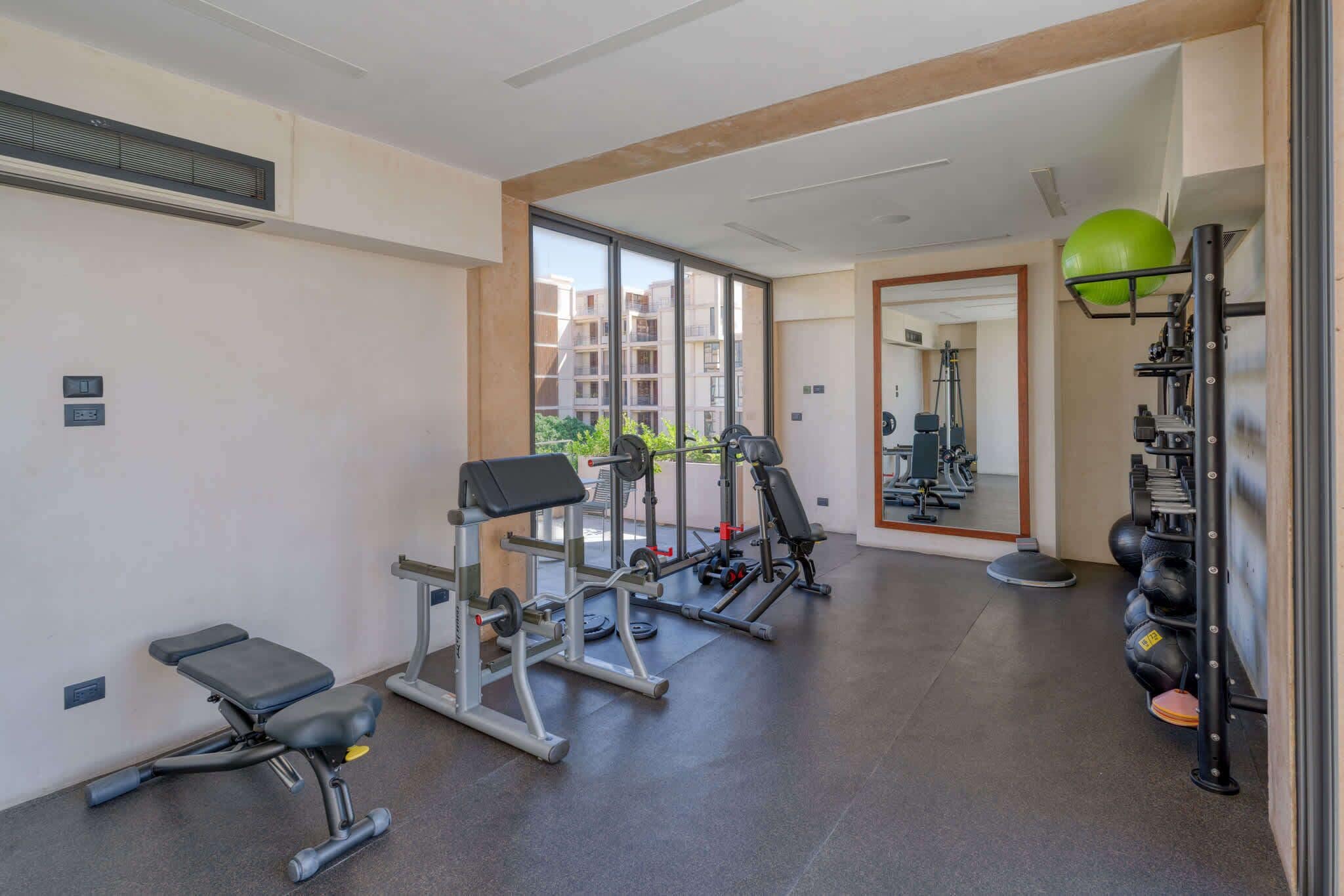 A gym with exercise equipment, a bench, and a mirrored wall.