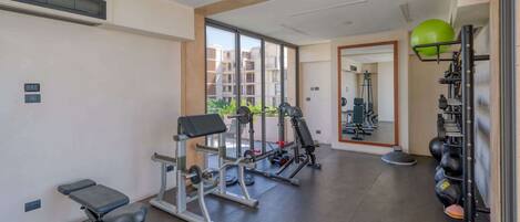 A gym with exercise equipment, a bench, and a mirrored wall.