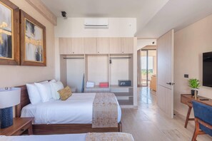 Ein modernes Hotelzimmer mit Bett, Nachttisch, Kleiderschrank und Schreibtisch mit Stuhl.