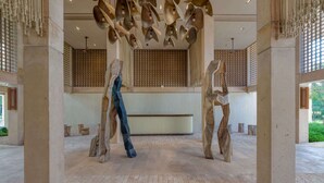 Een ruime lobby met een hoge plafond, grote zuilen en een centrale sculptuur.