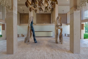 A spacious lobby with a high ceiling, large columns, and a central sculpture. - Chic 2BR Getaway in Corasol Playa (Playa del Carmen)