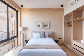 A hotel room with a bed, a bedside table, a lamp, a wardrobe, and two framed pictures on the wall. - Chic 2BR Getaway in Corasol Playa (Playa del Carmen)