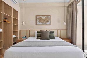 Ein Hotelzimmer mit Bett, Kleiderschrank, Nachttisch, einem gerahmten Kunstwerk und einem Fenster mit Vorhängen.