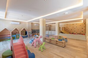 Ein Kinderspielbereich mit weichen Spielgeräten, einer Rutsche und einem Ballbecken.