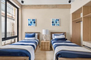 A hotel room with two beds, a wooden wardrobe, and artwork on the walls. - 2BR Resort Condo near Beach & Golf (Playa del Carmen)