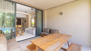 Ein modernes Interieur mit einem Holzesstisch, einer Couch und Blick auf einen Pool durch eine Glastür.