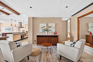 A modern living room with a sofa set, a coffee table, and a rug. There is a kitchen in the background with a dining area. - Bright 2BR Retreat near Golf & Beach (Playa del Carmen)