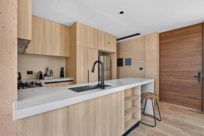 A modern kitchen with wooden cabinets, a white countertop, a gas stove, and a black faucet. - 1BR Retreat in Corasol, Playa del Carmen (Playa del Carmen)