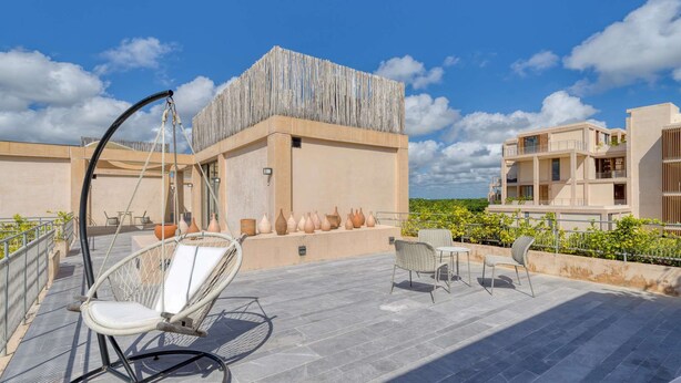 Eine Dachterrasse mit Sitzgelegenheiten im Freien, Topfpflanzen und Blick auf die umliegenden Gebäude.