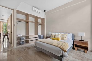 A bedroom with a bed, bedside tables, a wardrobe, and a built-in air conditioning unit. - Spacious 2BR with Terrace in The Village (Playa del Carmen)