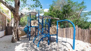A playground with a slide, climbing structures, and swings. - Spacious 2BR with Terrace in The Village (Playa del Carmen)