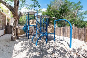 Ein Spielplatz mit Rutsche, Klettergerüsten und Schaukeln.