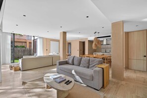 Un salon moderne avec un canapé gris, une table basse et un coin repas doté de meubles en bois.