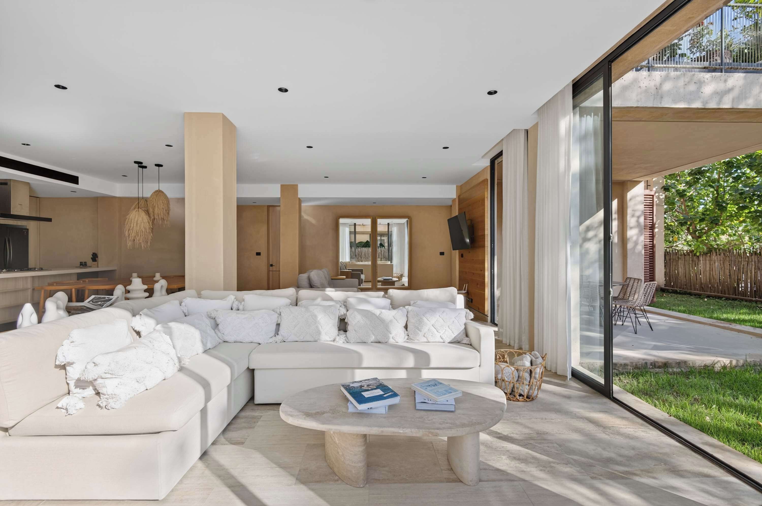 A modern living room with a large sectional sofa, a coffee table, and a view of the outdoors.