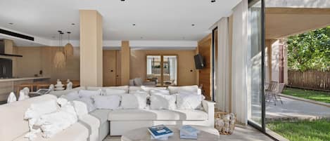 A modern living room with a large sectional sofa, a coffee table, and a view of the outdoors.