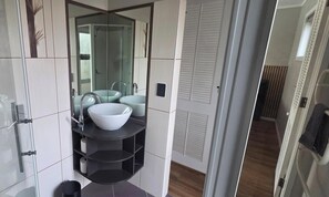 A modern bathroom with a large mirror, two sinks, and a black shelf unit.