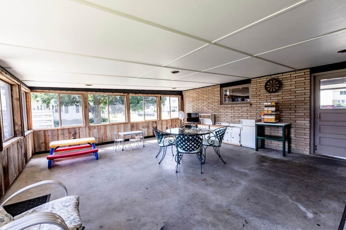 Un espace extérieur abrité comprenant une table et des chaises, un banc et un jeu de fléchettes fixé au mur.