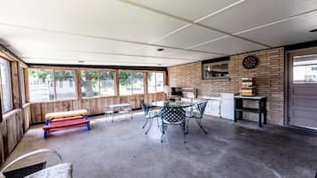 Un espace extérieur abrité comprenant une table et des chaises, un banc et un jeu de fléchettes fixé au mur.