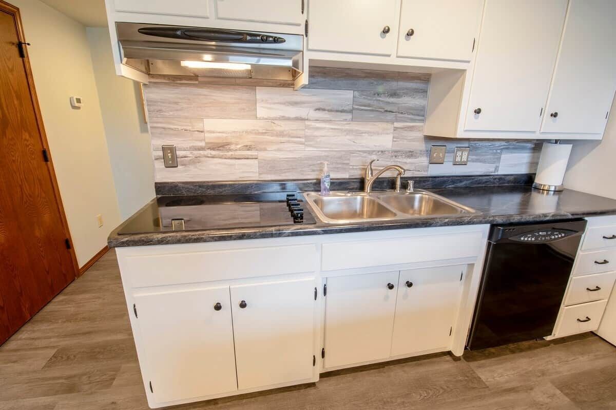 A modern kitchen with white cabinetry, a double sink, and a dishwasher.