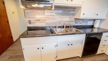 A modern kitchen with white cabinetry, a double sink, and a dishwasher.