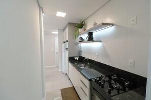 A modern kitchen with white cabinets, a black countertop, and a gas stove. - Family Apartment III near Beto Carrero World and the Beach (Penha)