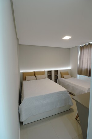 Ein Hotelzimmer mit zwei Betten, einem Nachttisch, einem Kleiderschrank und einer Deckenleuchte.