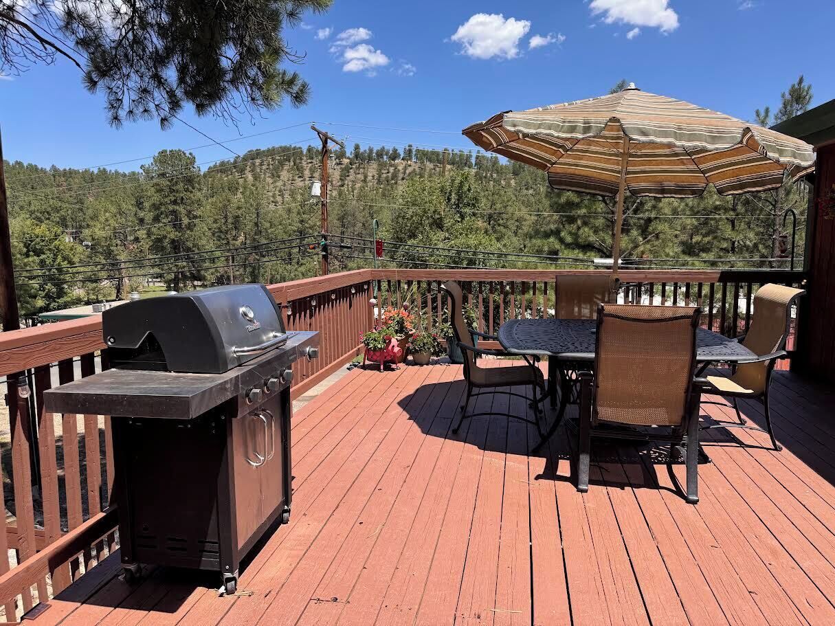 A deck with a grill, outdoor table, chairs, and an umbrella.