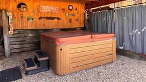 En træhytte med jacuzzi, en træbænk og et skilt, der står 'COLD BEER'.