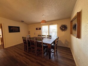 A dining area with a wooden table and chairs, a ceiling light, and a window with blinds. - Come and enjoy a relaxing getaway in beautiful Ruidoso! Minutes from everything (Ruidoso)