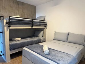 Una cama litera con una cama inferior y otra cama individual a la derecha.