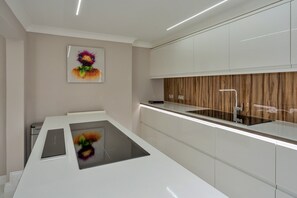 A modern kitchen with white cabinetry, a wooden backsplash, and a central island with a black countertop.
