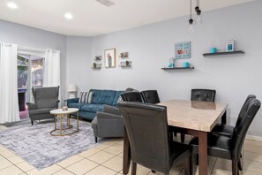 A modern living room with a dining area, featuring a sofa set, a coffee table, and a dining table with chairs. - Magic 3B/3B Family Escape/Near Parks (Kissimmee)